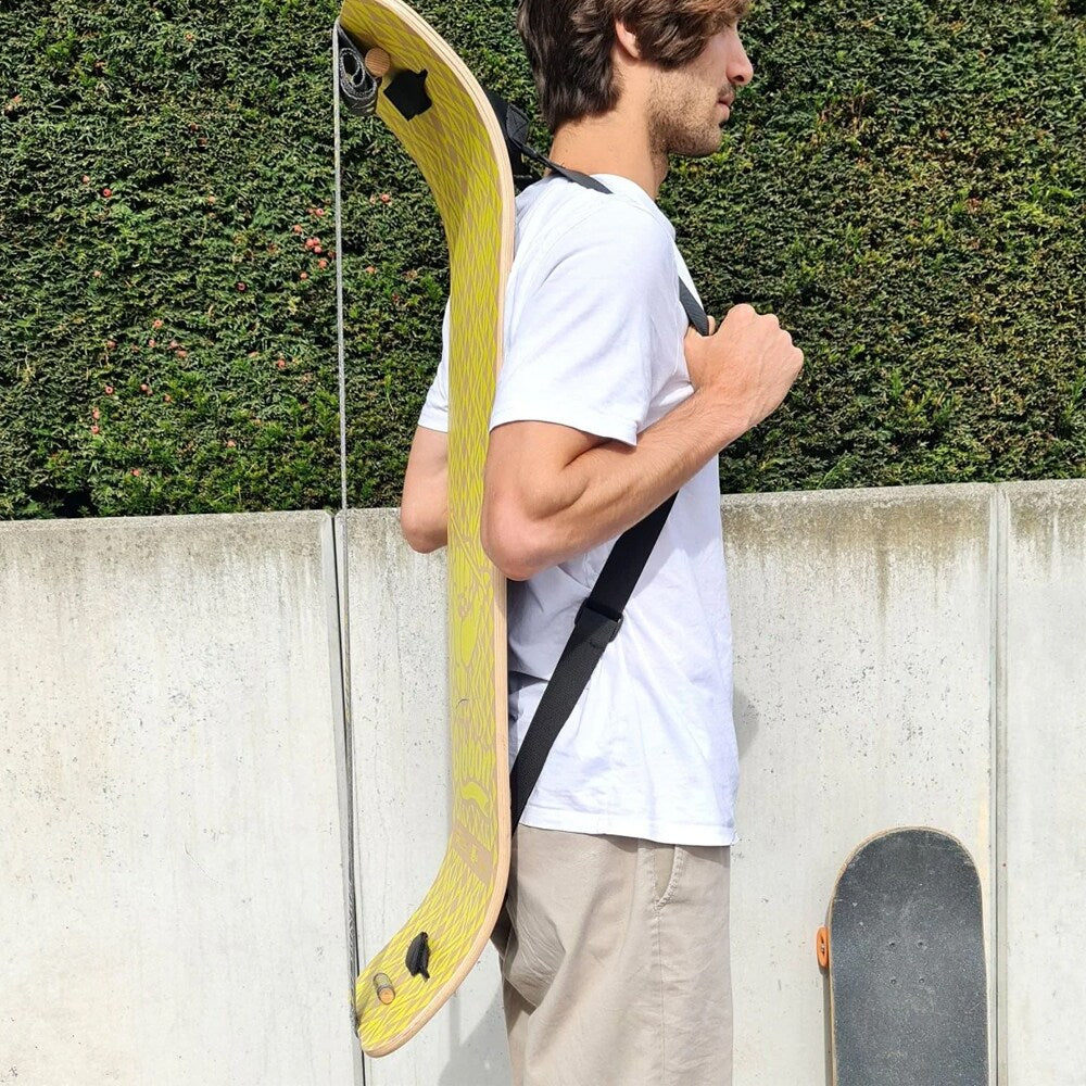 Närbild på en man i profil som bär en gulmönstrad GIBBOARD vertikalt på ryggen med hjälp av en svart GIBBON Shoulderstrap.