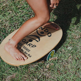 Närbild på fötter som balanserar barfota på en Indoboard balansbräda med roller på gräs