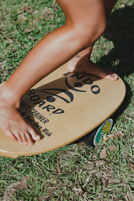Närbild på fötter som balanserar på en Indoboard balansbräda med roller på gräs