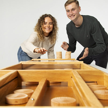 Två spelare spelar Dutch Shuffle med träpuckar