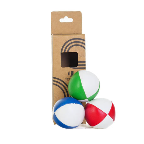 Tre flerfärgade jongleringsbollar från Firetoys i färgerna rött, grönt och blått, fotograferade framför sin bruna kartongförpackning