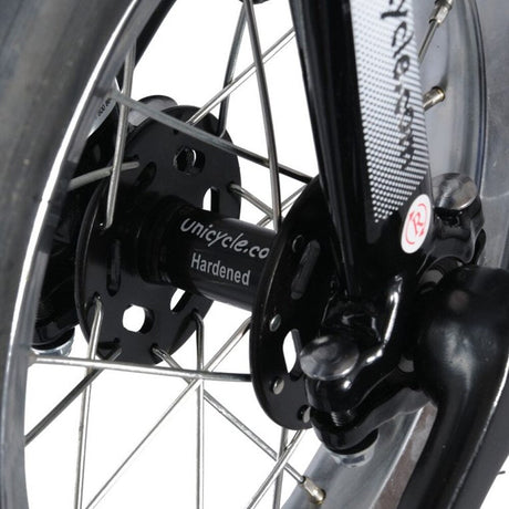 Närbild på svart nav märkt "Unicycle.com Hardened" på en Hoppley 12 tums enhjuling. Visar silverekrar och svart gaffel