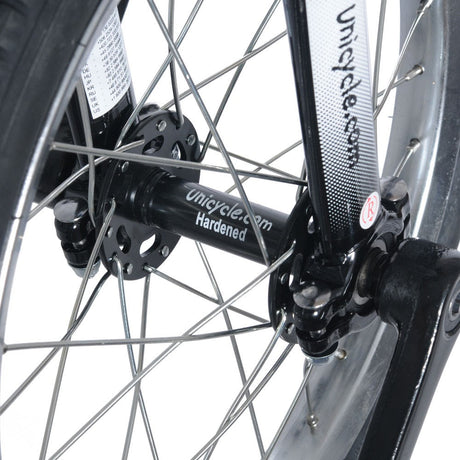 Närbild på svart nav märkt "Unicycle.com Hardened" och svart gaffel på en enhjuling. Visar nav, ekrar och vevarmens fäste