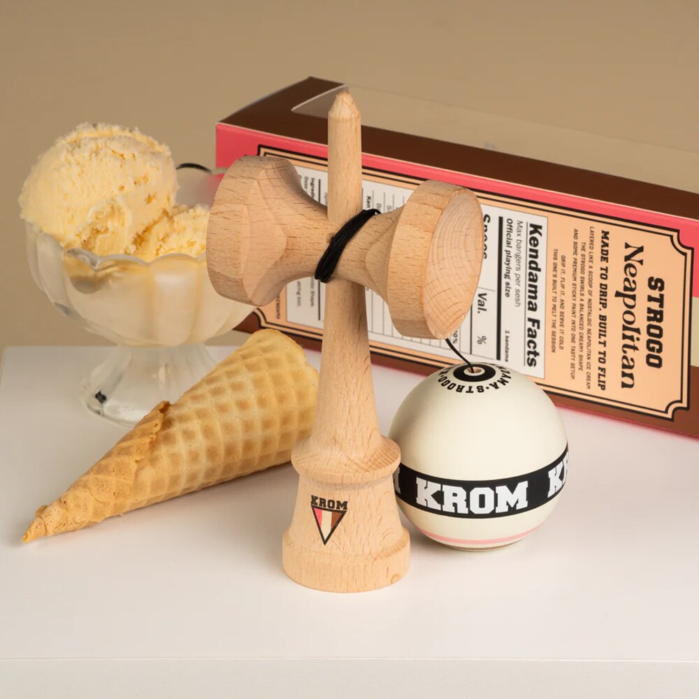 KROM Strogo Neapolitan kendama i ljust trä uppställd bredvid sin temaförpackning tillsammans med en glasskål med vaniljglass och en tom glasstrut på en vit yta.