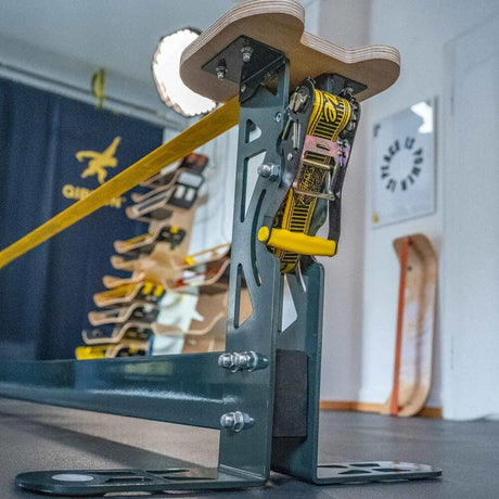 Närbild på en robust stålkonstruktion för GIBBON Slackrack XL Upgrade med en gul Slackline spänd genom en kraftig spärrhake i en träningsmiljö