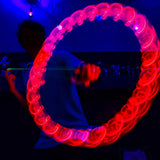 Actionbild i ett mörkt rum som visar en jojo med röda LED-lampor som skapar en lysande cirkel genom rörelse. I bakgrunden syns konturerna av en person upplyst av blått ljus.