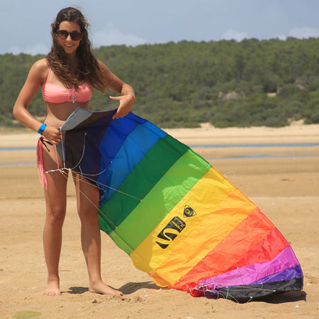 Kvinna på en strand som förbereder en färgglad Symphony Beach 2.2 paragliderdrake med vitt snöre