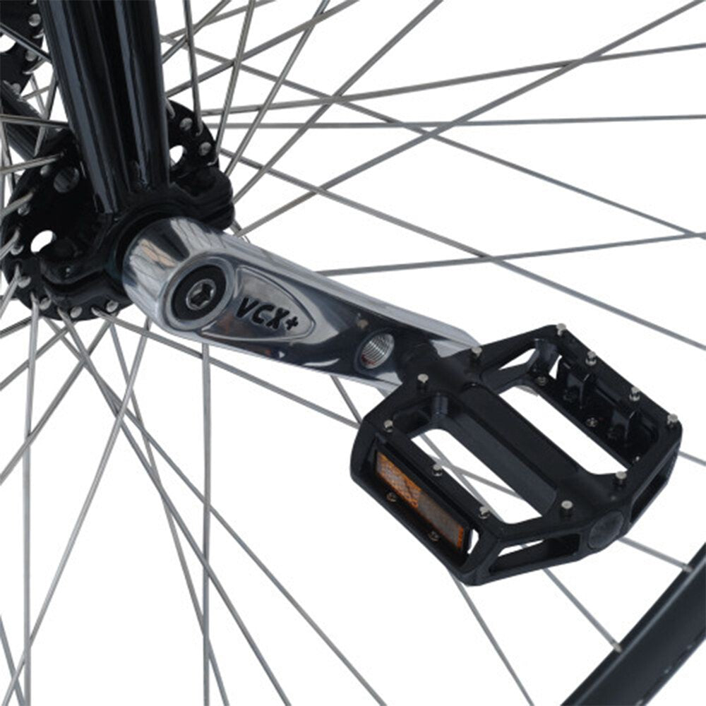 Närbild på höghjulingens nav och vevarm. Visar Nimbus VCX Plus-vevarmar i polerat stål och svarta aluminiumpedaler med dubbar