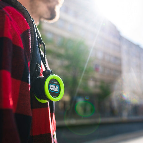 Limegrön YoYoFactory ONE-jojo hängande i en svart hållare på axeln av en person i rödsvart rutig skjorta utomhus.