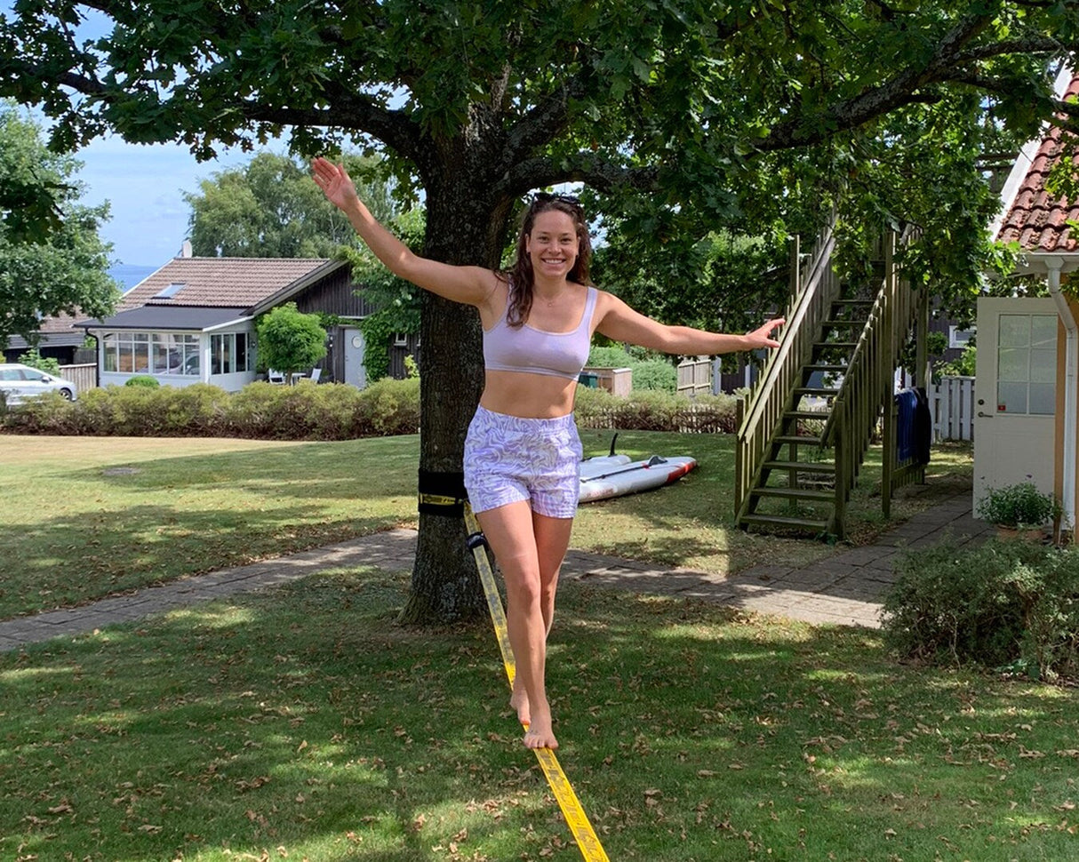 Tjej går på en Gibbon ClassicLine slackline – balans och rörelse i naturen