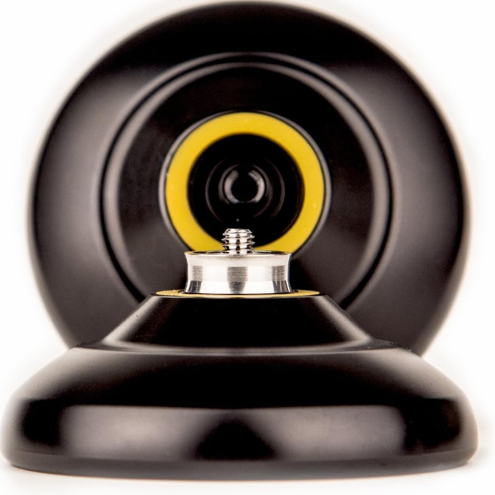 Extrem närbild på en isärplockad svart jojo som visar den inre axeln och kullagret i silver. I bakgrunden syns den andra halvan av jojon med en gul responsring i mitten mot en vit bakgrund.